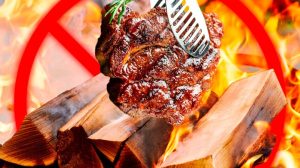 Person grilling meat over wood