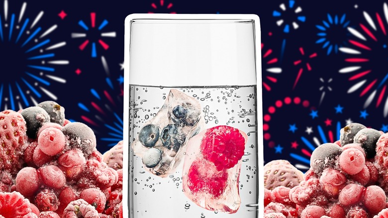 a drink with fruity ice cubes in front of fireworks