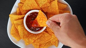 dipping chips into spicy sauce