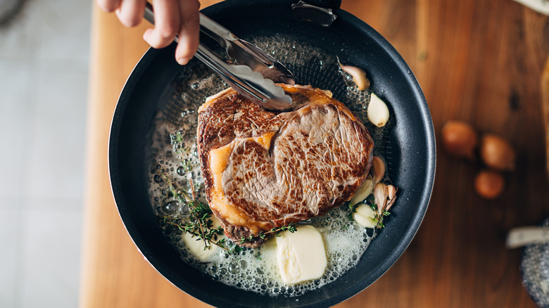 Chef preparing ribeye with butter